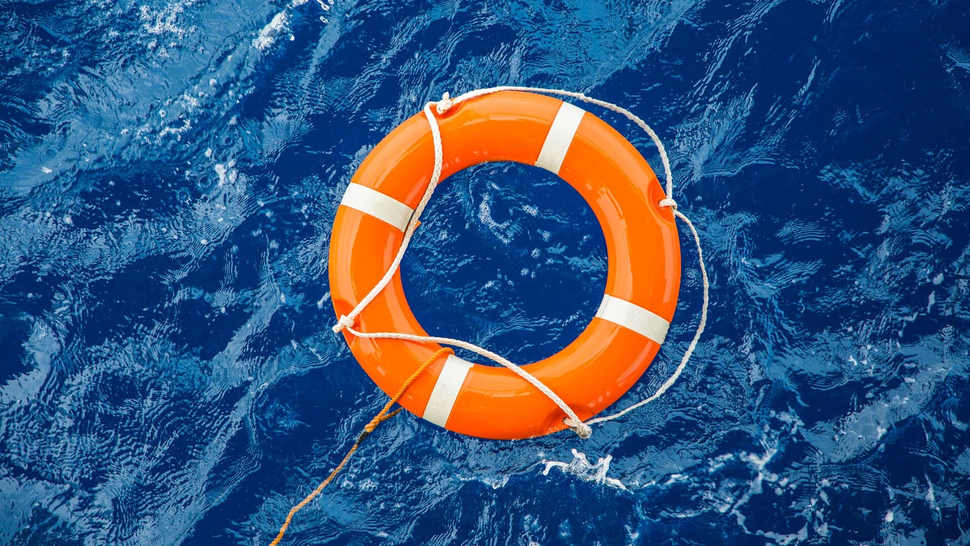 Orange lifebuoy floating on choppy blue water