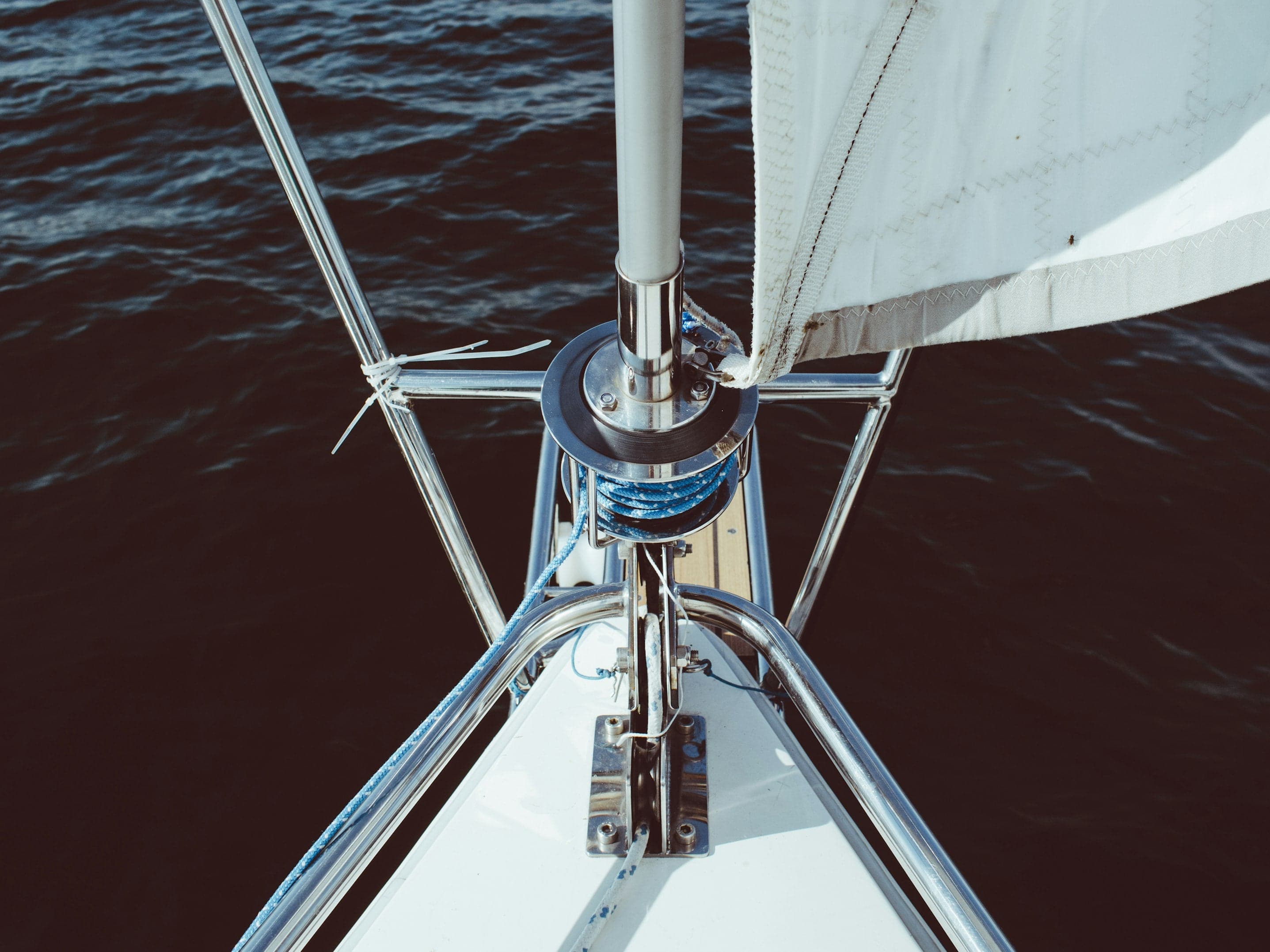 Looking down at a yacht's mast base and furled headsail from above the foredeck